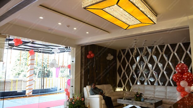 A modern hotel lobby with a seating area, a decorative chandelier, and a view of the outdoors. - Hotel Ramaya  (Gwalior)