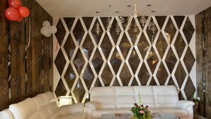A modern living room with a white sofa, a glass coffee table, and a decorative wall with geometric patterns. - Hotel Ramaya  (Gwalior)
