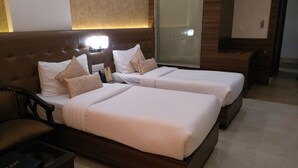A hotel room with two beds, a wooden headboard, a nightstand, and a mirror. - Hotel Ramaya  (Gwalior)