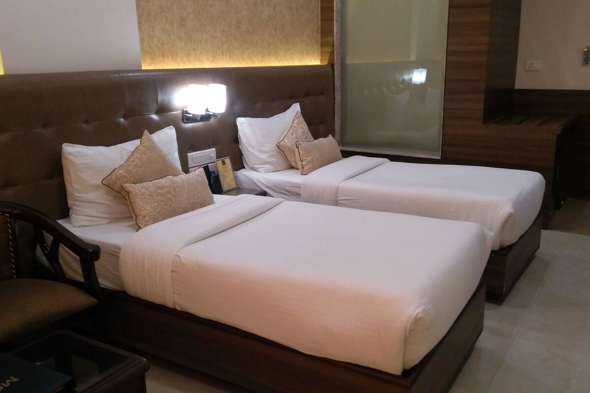 A hotel room with two beds, a wooden headboard, a nightstand, and a mirror.