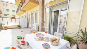 An outdoor patio with a table set for a meal, surrounded by potted plants and outdoor furniture. - La Terrazza di Andrea (Imperia)