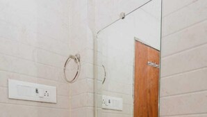 A bathroom with a white sink, a mirror, and a towel ring on the wall. - Hotel Purple Orchid (Mumbai)