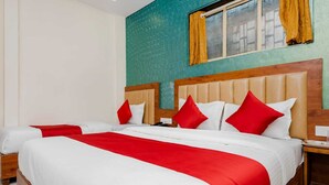 A hotel room with a large bed, two bedside tables, and a window with curtains. - Hotel Purple Orchid (Mumbai)