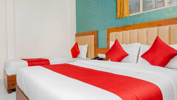 A double bed with white and red bedding, a wooden headboard, and a telephone on the nightstand. - Hotel Purple Orchid (Mumbai)