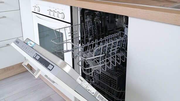 Une cuisine moderne équipée d’un lave-vaisselle encastré, d’une machine à café et d’une bouilloire posées sur le plan de travail.