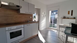 Une cuisine moderne avec des meubles blancs, un plan de travail en bois et un four encastré.