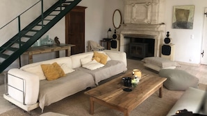 Un salon comprenant un canapé, une table basse, une cheminée et un escalier.