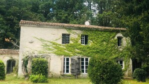 Un bâtiment à deux étages, doté d’un toit en tuiles et entouré d’une végétation luxuriante.