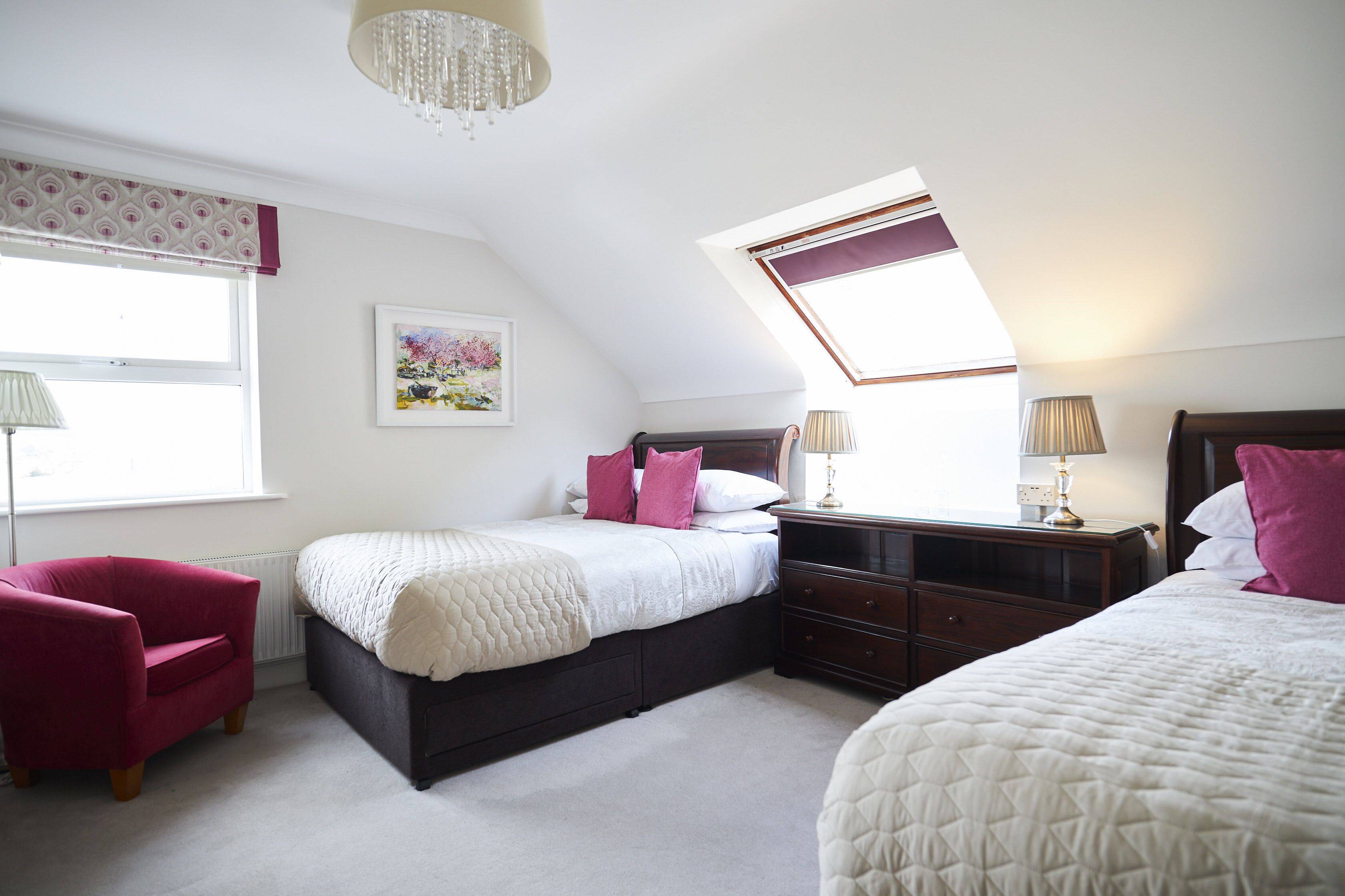 Een slaapkamer met een bed, een stoel, een nachtkastje en een raam met uitzicht.