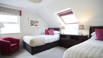Een slaapkamer met een bed, een stoel, een nachtkastje en een raam met uitzicht.