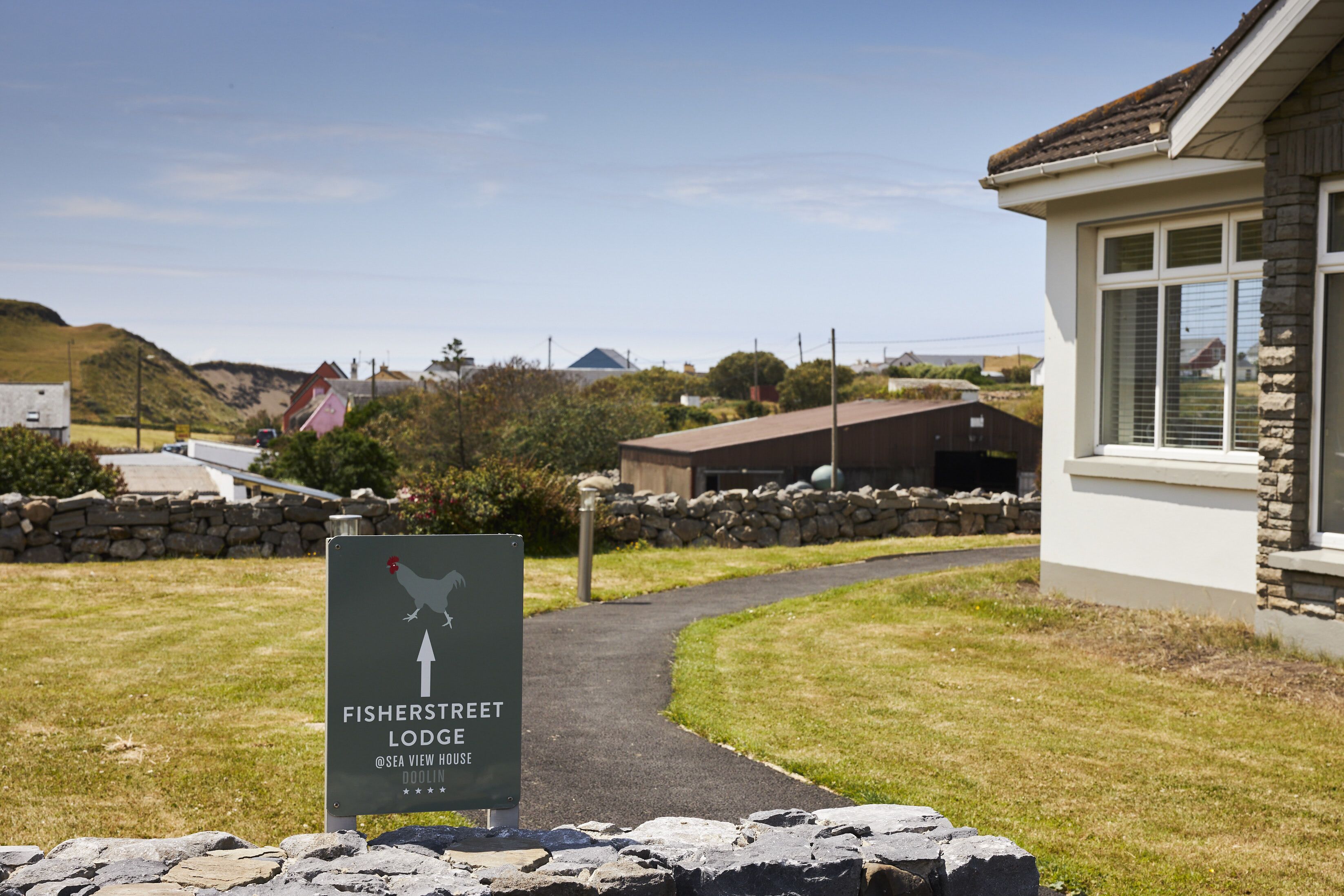 A sign for Fisherstreet Lodge with a pathway leading to the building.
