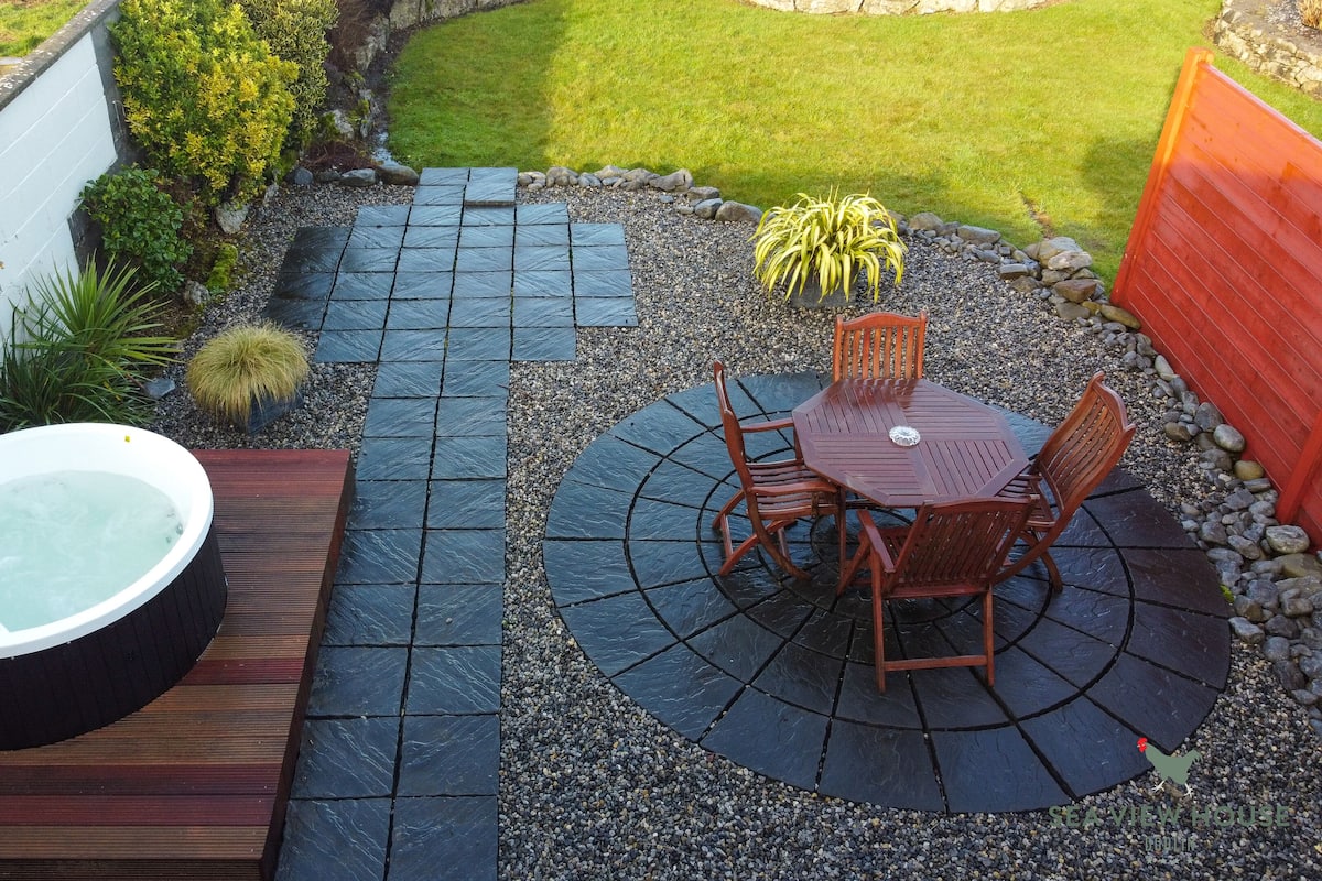 Ein Whirlpool, eine Holzterrasse und eine Sitzgruppe im Freien mit Tisch und Stühlen.