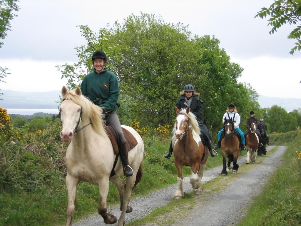 Un grupo de personas montando a caballo por un sendero estrecho rodeado de follaje.