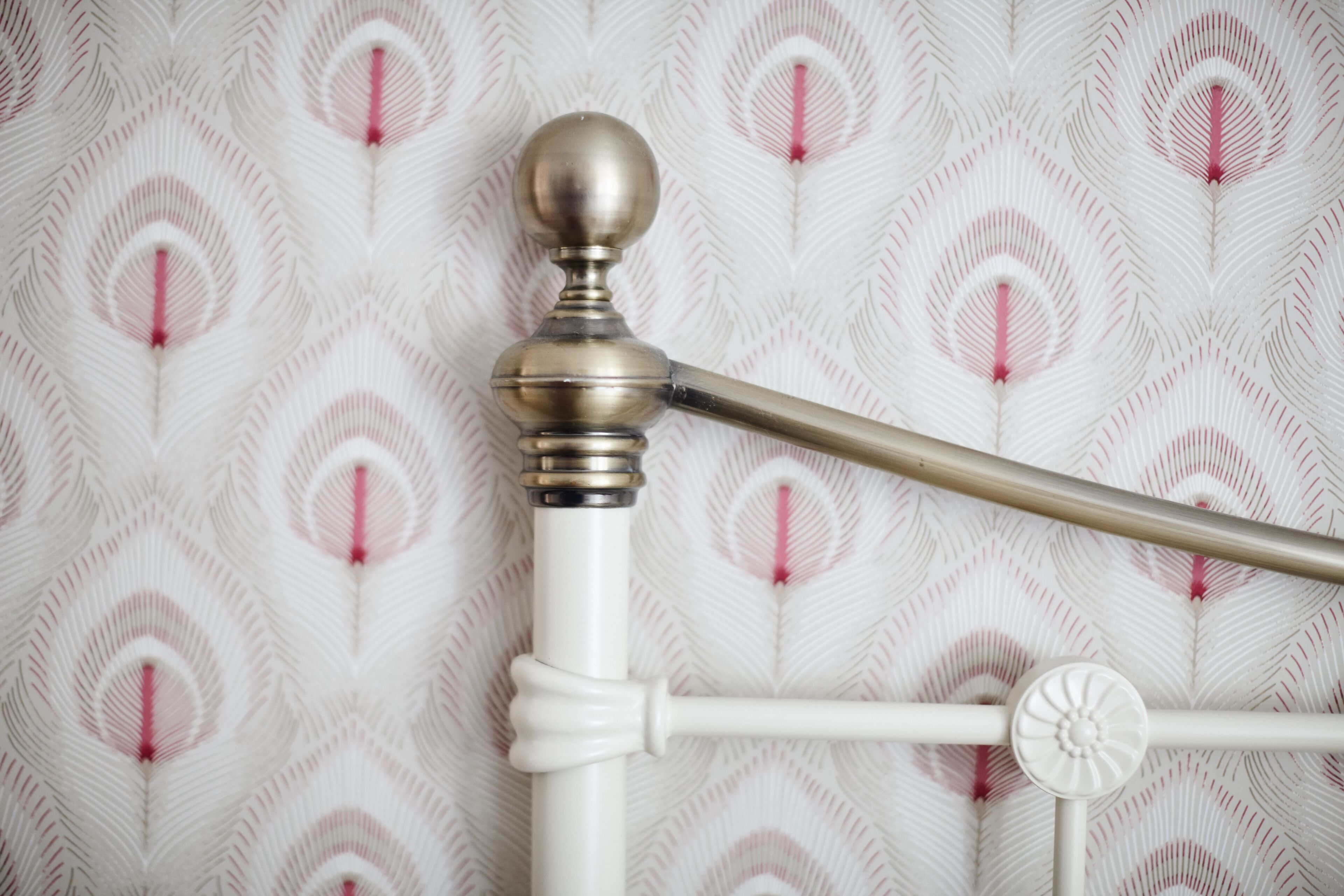 A white metal bed frame with a round finial and a horizontal bar.