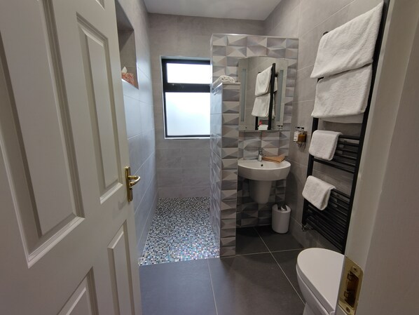 A modern bathroom with a shower, sink, and toilet.