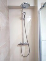 Una ducha con cabezal de ducha de mano y un cabezal fijo montado en la pared.