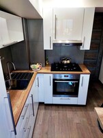 Una cocina compacta con horno integrado, cocina y fregadero.