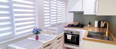 A modern kitchen with white cabinets, a wooden countertop, and a built-in oven.