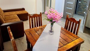 Een eethoek met een houten tafel, stoelen en een vaas roze bloemen.