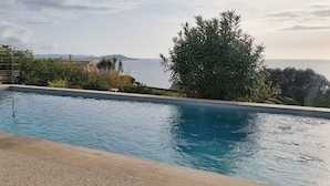 A rectangular swimming pool with clear blue water, surrounded by a pebble deck.