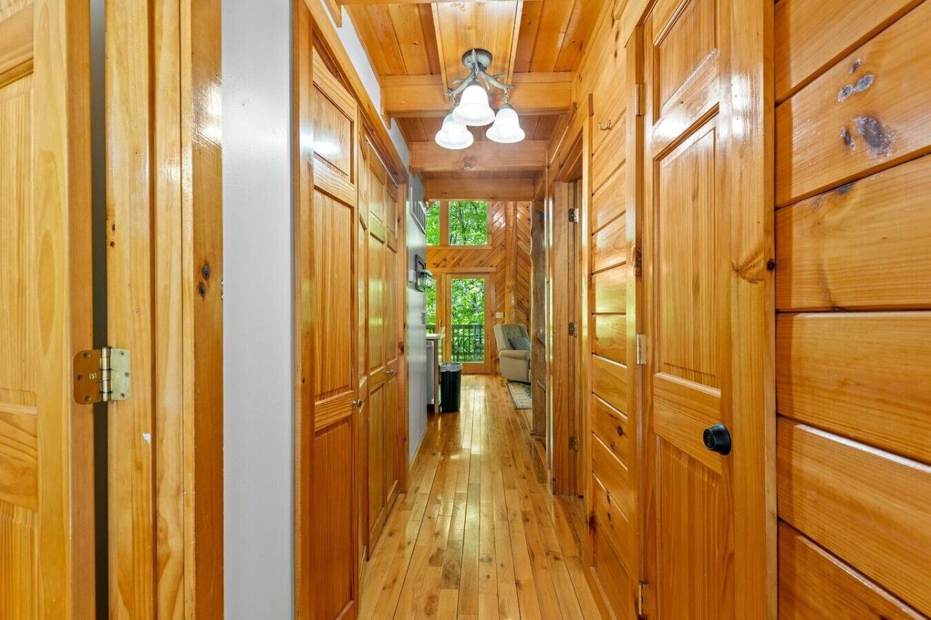 Un couloir en bois avec un luminaire au plafond et une vue sur un balcon.