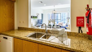 A kitchen with granite countertops, stainless steel sink, wooden cabinets, and a fire extinguisher. - Downtown Charming Condo Close to Dubai Mall (Dubai)