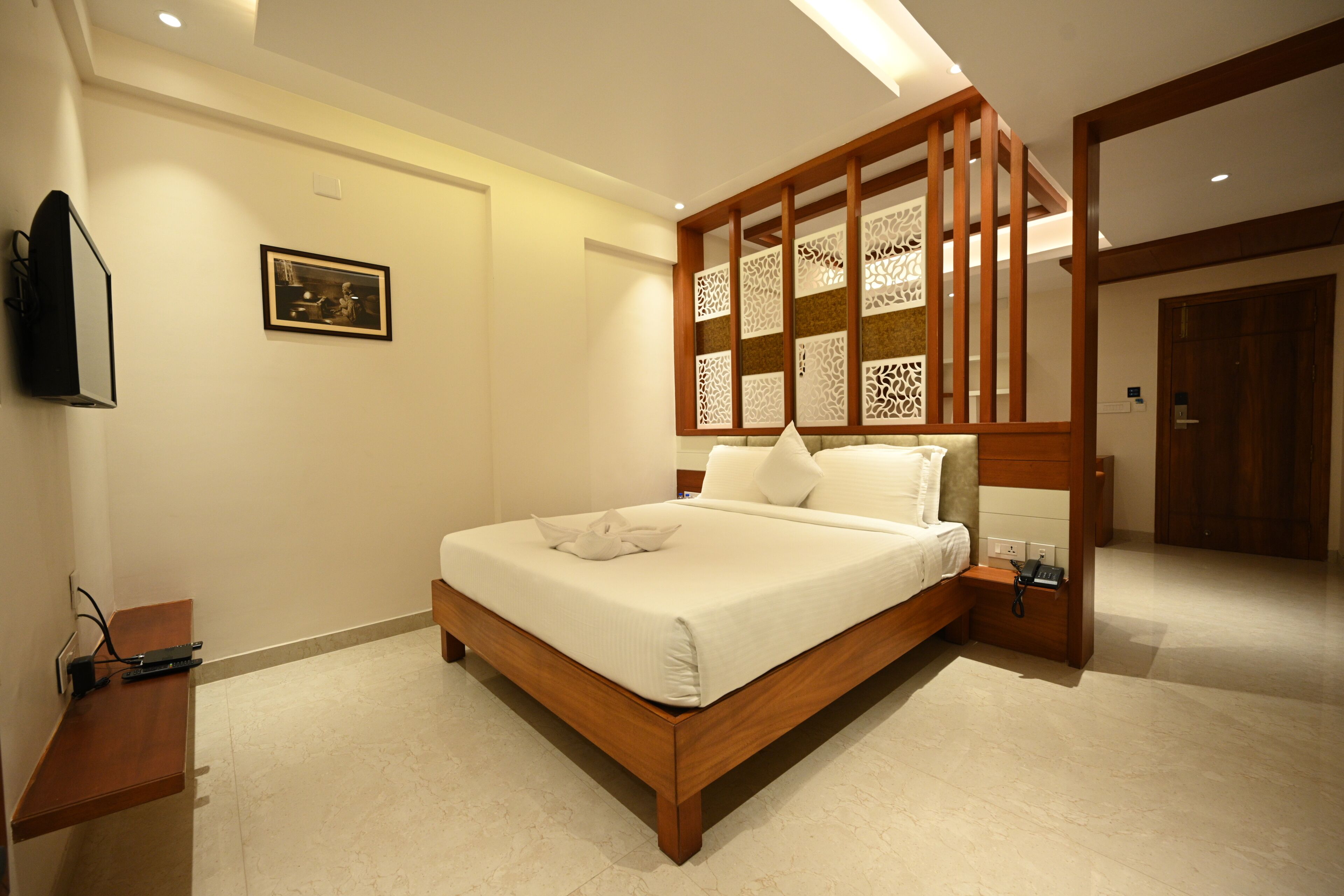A modern bedroom with a wooden bed frame, a bedside table, and a decorative panel on the wall.