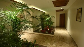 A hallway with a tiled floor, potted plants, and a wooden ceiling. - Chithara Comforts (Udupi)