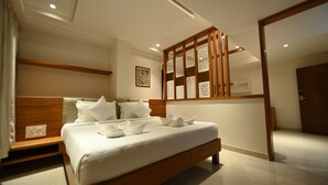 A modern hotel room with a large bed, wooden headboard, and a decorative partition. - Chithara Comforts (Udupi)