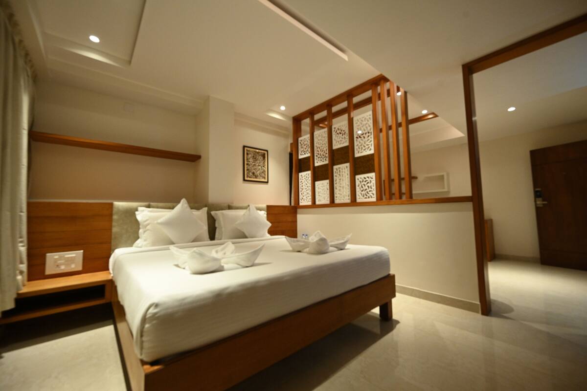 A modern hotel room with a large bed, wooden headboard, and a decorative partition.