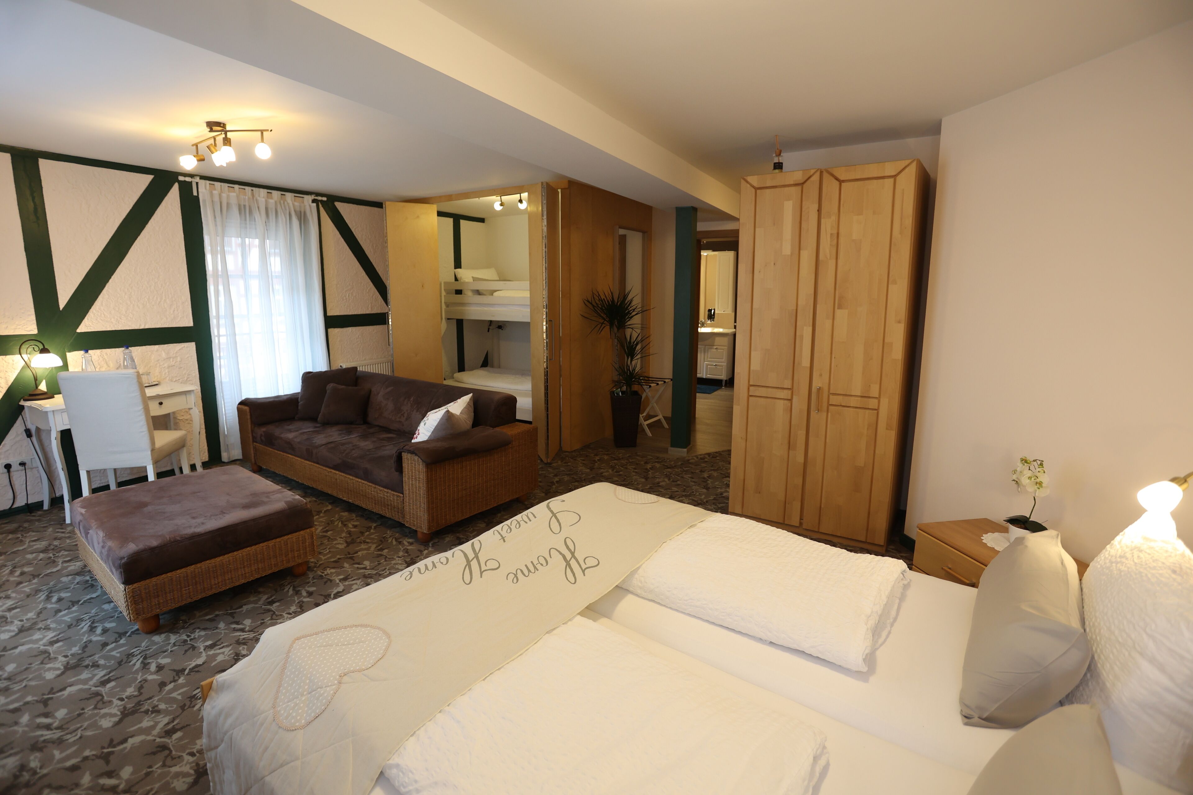 A bedroom with a bed, a sofa, a desk, and a wardrobe.