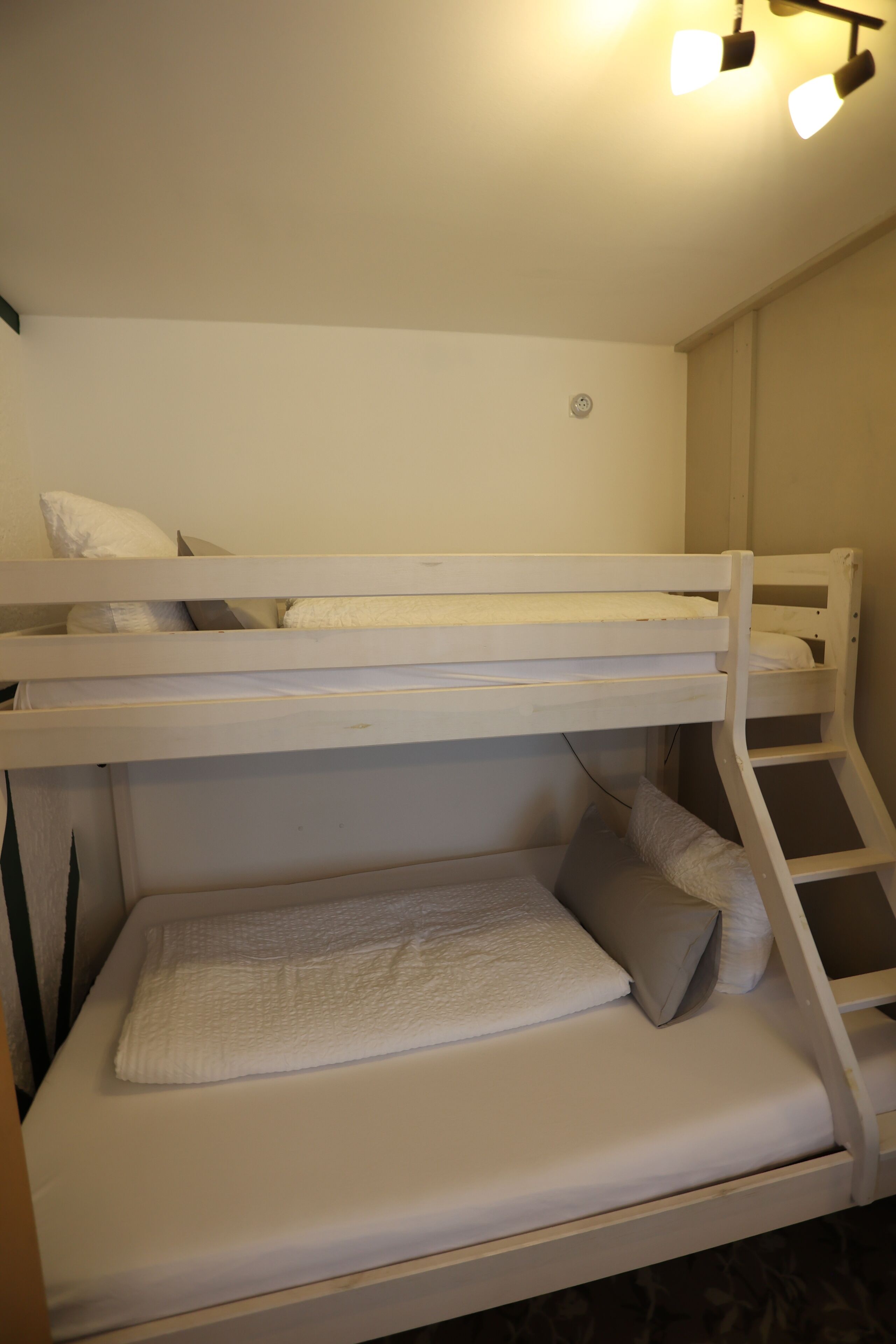 A bunk bed with a ladder, a white headboard, and a small shelf.