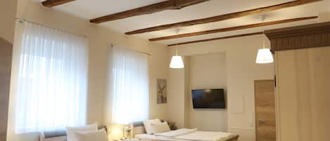 A bedroom with two beds, wooden beams, a TV, and a wardrobe.