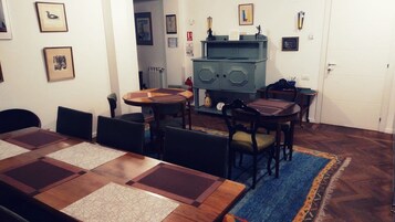 A dining area with a wooden table and chairs, a blue rug, and a vintage stove in the background.