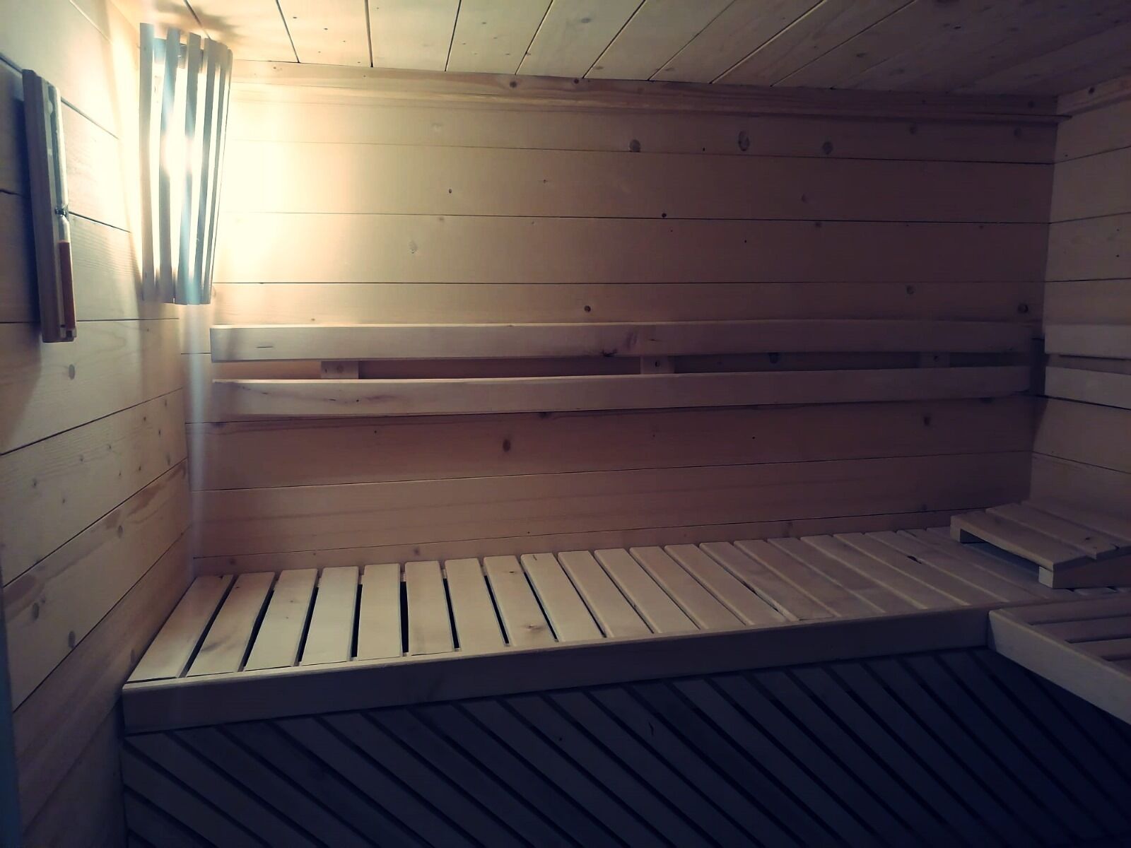A sauna with wooden benches and a sloped floor.