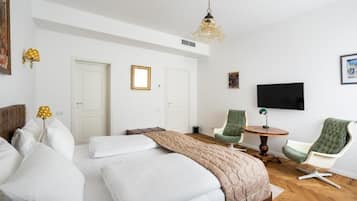 Una habitación de hotel con una cama, dos sillas, un televisor y una lámpara.