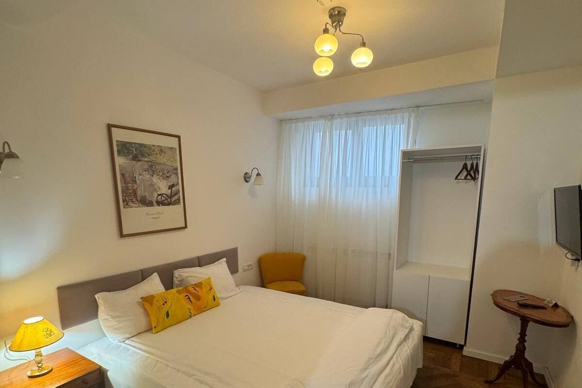 A hotel room with a bed, a desk with a lamp, a chair, a wardrobe, and a television.