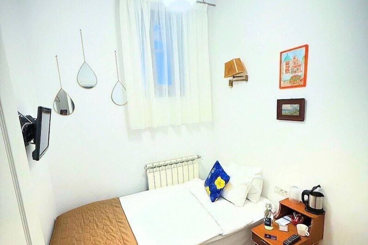 A small, neatly arranged bedroom with a bed, bedside table, and a radiator.