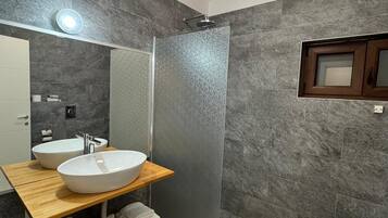 Un baño moderno con dos lavamanos, ducha e inodoro.