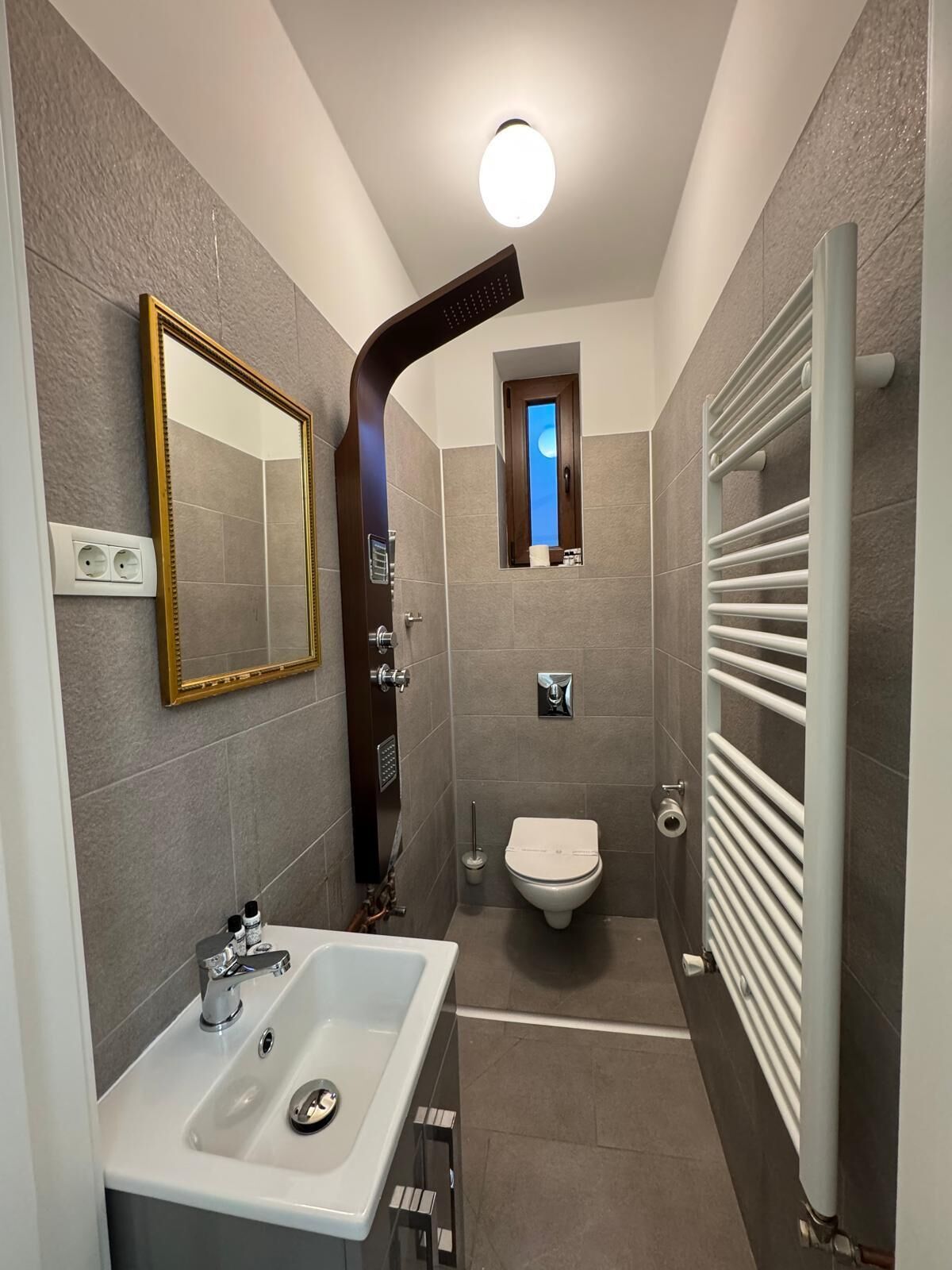 A modern bathroom with a large mirror, a sink, a toilet, and a shower.