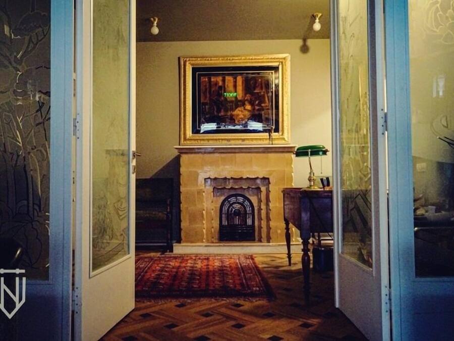 A room with a fireplace, a framed picture above it, and a patterned rug on the floor.