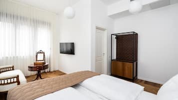 Una camera d'albergo moderna con un letto grande, un comodino, uno specchio, una TV e un armadio.