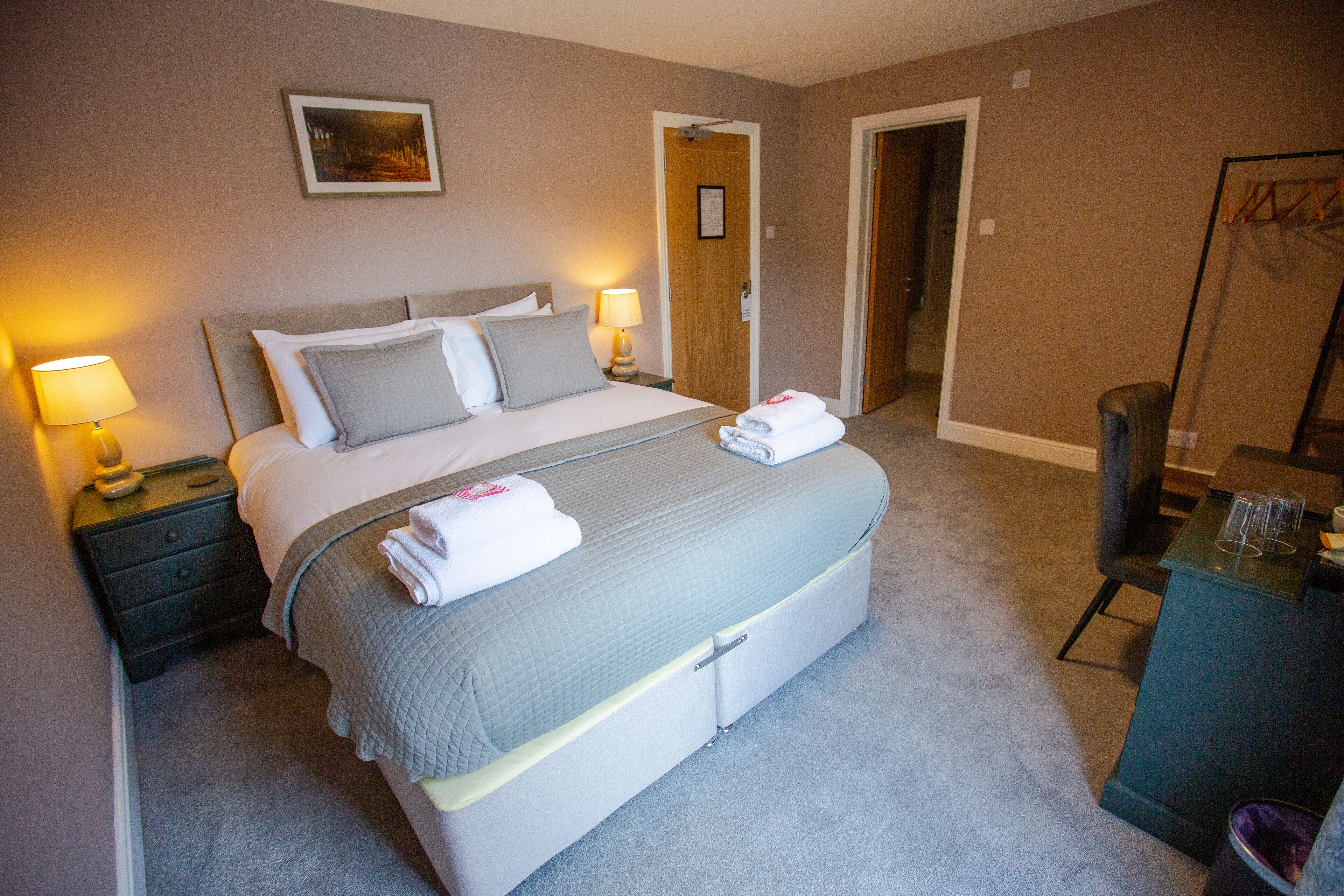 A neatly made bed with pillows, a bedside lamp, and a folded towel on the bed.