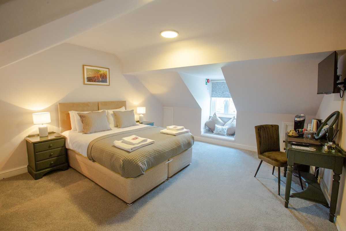 A bedroom with a bed, a desk, a chair, and a window.