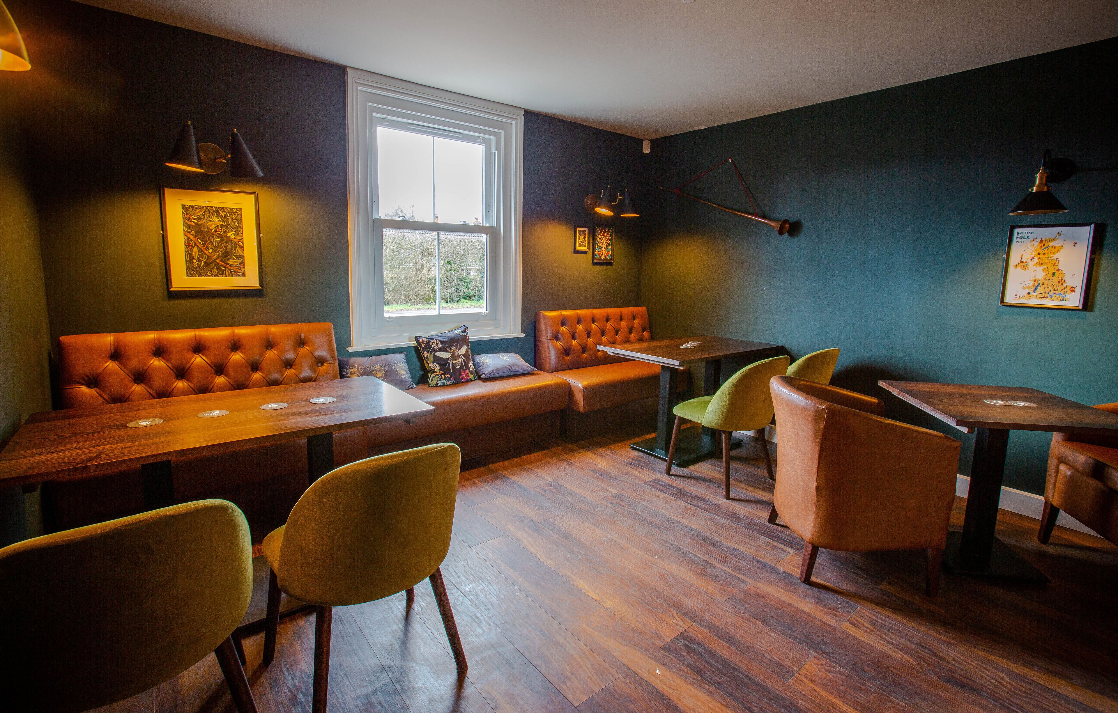 A cozy restaurant with wooden tables and chairs, a cushioned bench, and artwork on the walls.