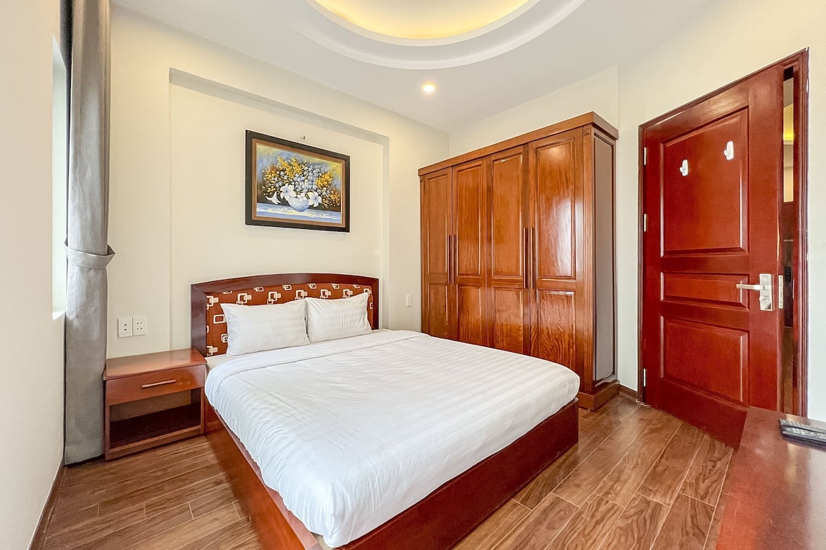 A bedroom with a wooden bed, a nightstand, a wardrobe, and a painting on the wall.