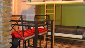 A compact room with a bunk bed, a dining table with chairs, and a hanging light fixture. - 3 minutes on foot from Piazza Navona and Castel Sant’Angelo and the Vatican! (Roma)