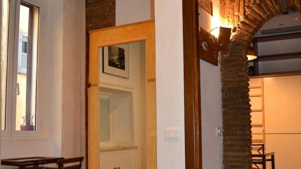 A room with a bed, a wooden table with chairs, a door leading to another room, and a tiled floor. - 3 minutes on foot from Piazza Navona and Castel Sant’Angelo and the Vatican! (Roma)
