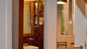A narrow hallway leading to a bathroom with a sink and mirror, a door with a glass panel, and a small window. - 3 minutes on foot from Piazza Navona and Castel Sant’Angelo and the Vatican! (Roma)