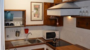 A compact kitchen with a sink, a microwave, and wooden shelves. - 3 minutes on foot from Piazza Navona and Castel Sant’Angelo and the Vatican! (Roma)